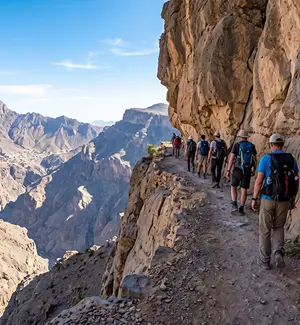 Hikers walking a narrow section of the W6 Balcony Walk trail on Jabal Shams