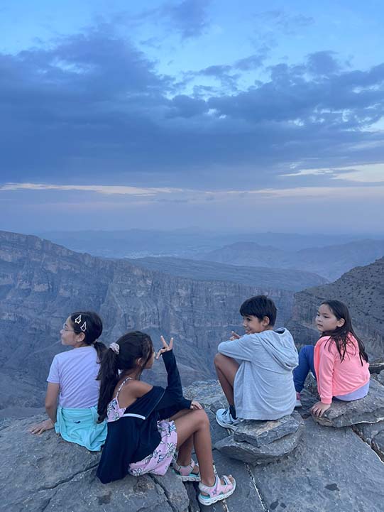 kids sitting on Jebel Shams rocks