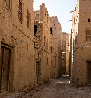 Towering mud-brick houses of Old Al Hamra lined up along a narrow lane