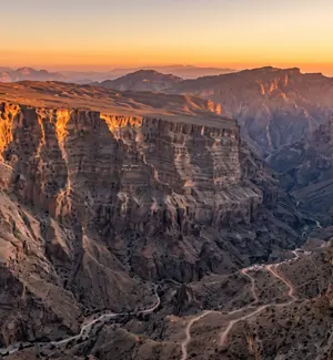 Layered limestone cliffs of Wadi Ghul, the Grand Canyon of Oman, at golden hour